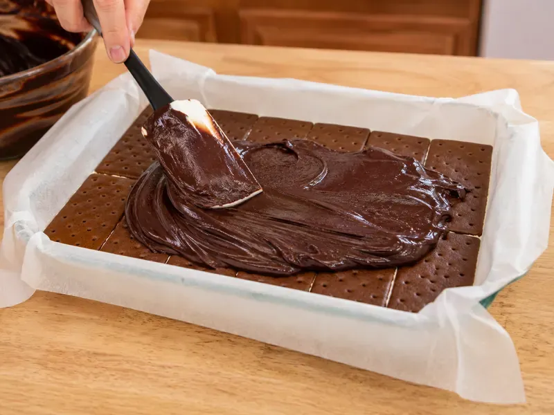 Hot fudge sauce spread over the first layer of ice cream sandwiches.