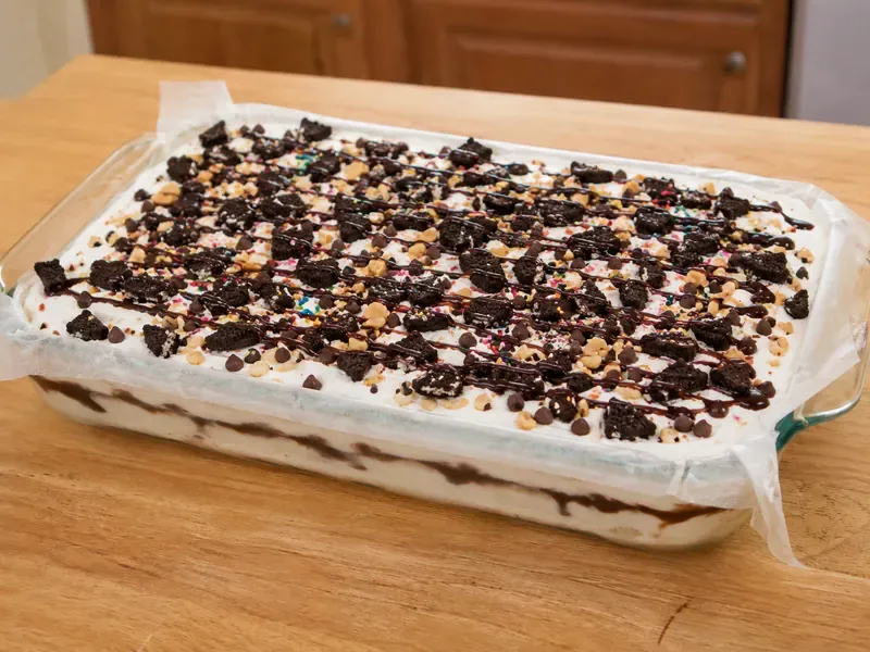 Ice cream sandwich dessert topped with chocolate drizzle, cookies, and chocolate chips.