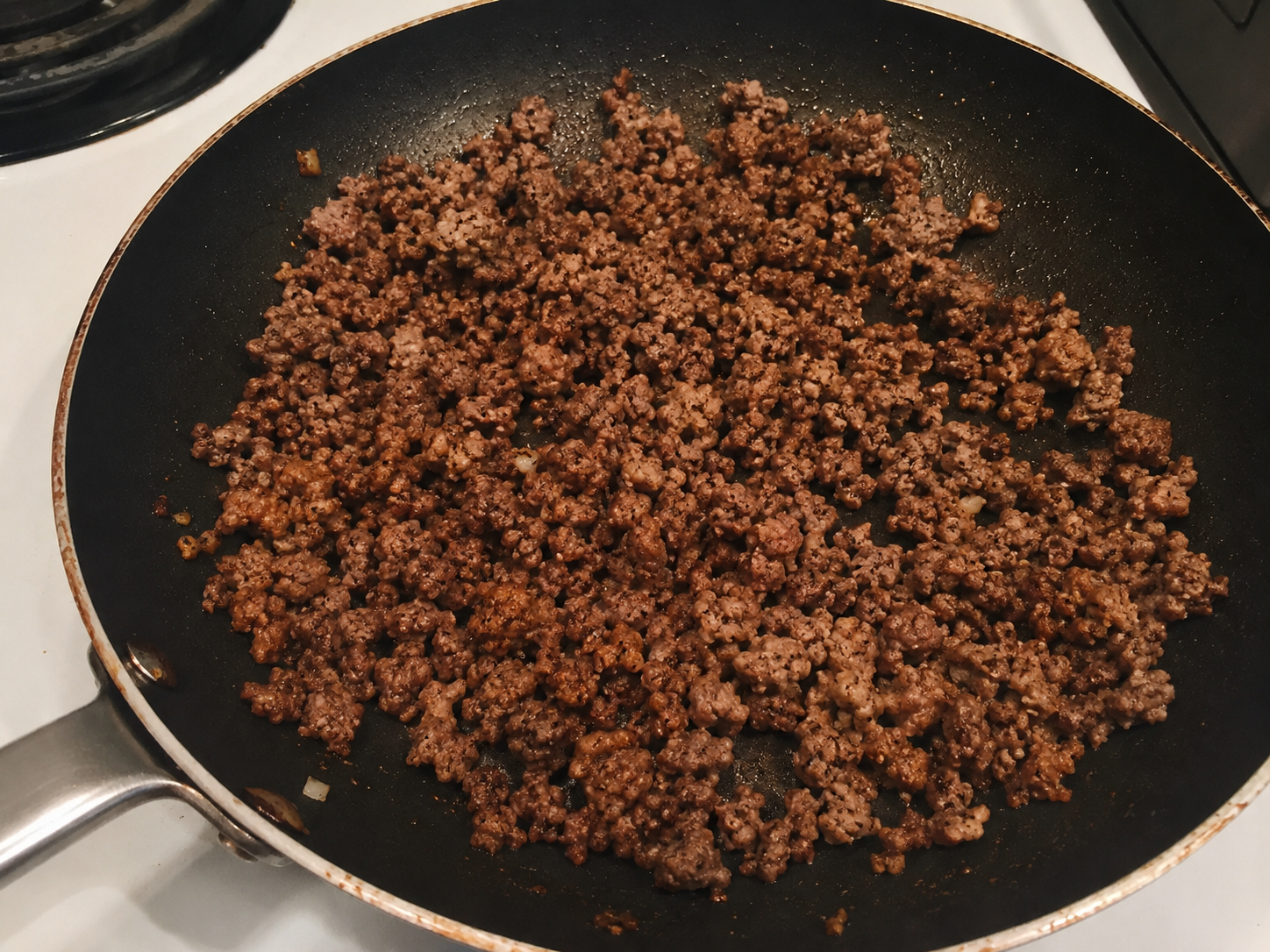 Ground beef cooking in a skillet with garlic and spices for a hot honey cottage cheese beef bowl.
