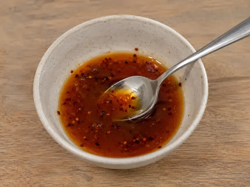 Hot honey sauce mixed with hot sauce and chili flakes in a small bowl.