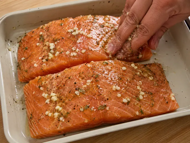Salmon fillets seasoned with olive oil, lemon juice, garlic, oregano, salt, and pepper.