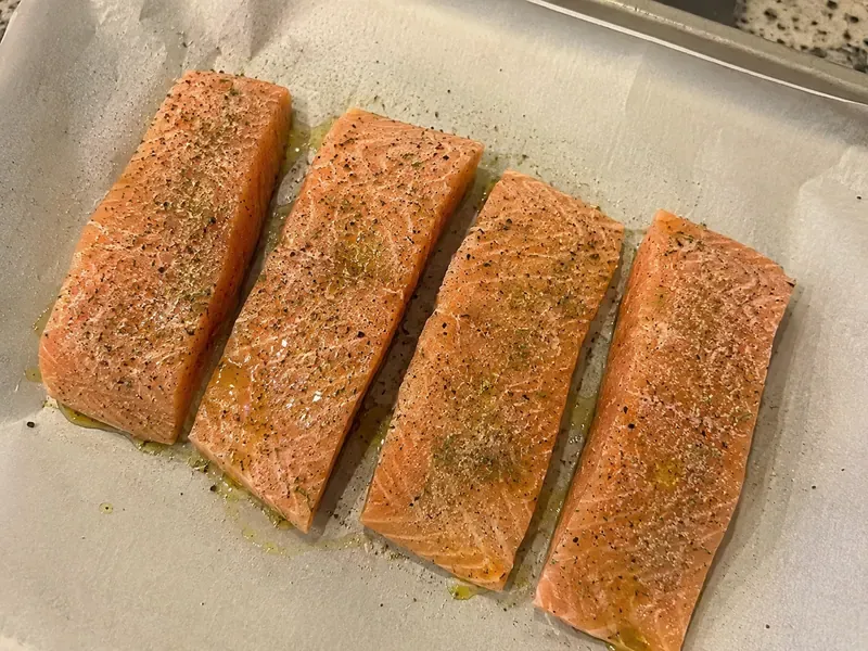 Salmon fillets seasoned with lemon juice, oregano, garlic powder, salt, and pepper.