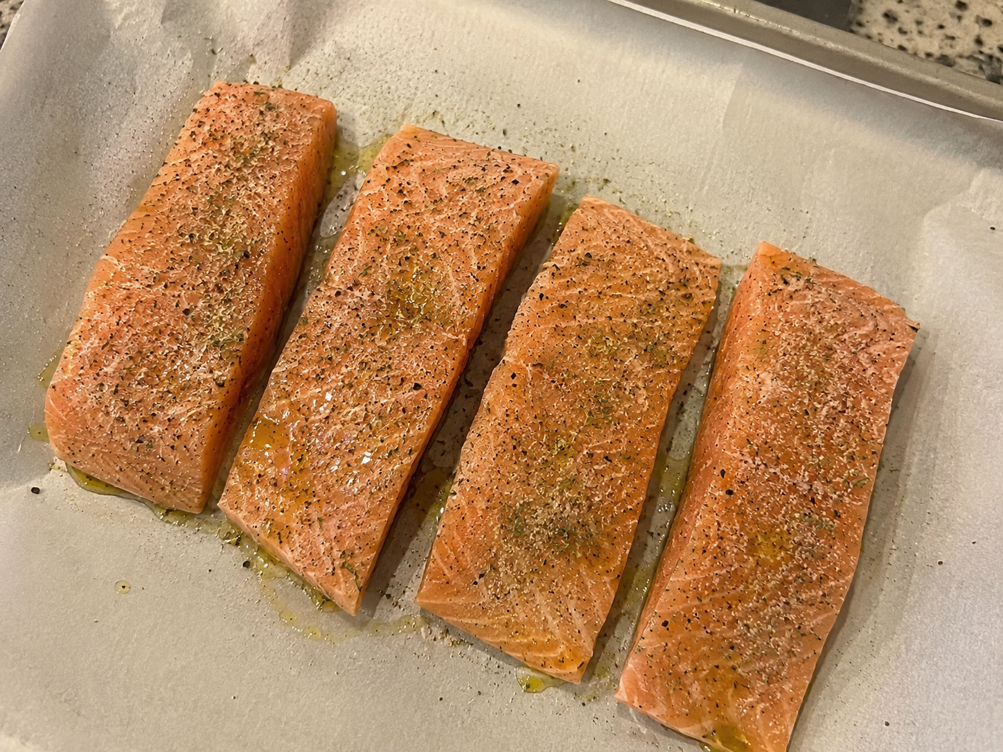 Salmon fillets seasoned with lemon juice, oregano, garlic powder, salt, and pepper.