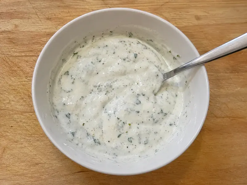 Lemon herb yogurt sauce mixed in a bowl with Greek yogurt, lemon juice, herbs, garlic powder, salt, and pepper.