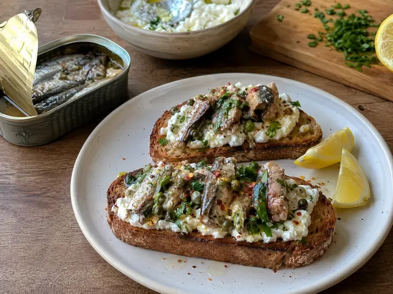 Finished Lemon Ricotta Sardine Toast topped with sardines, herbs, capers, chili flakes, and lemon.