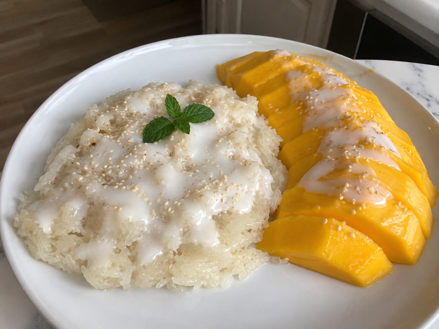 Mango Sticky Rice with coconut sticky rice, ripe mango slices, coconut sauce, and sesame seeds.