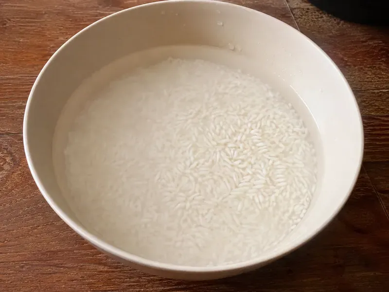 Thai glutinous rice rinsed and soaked in a bowl of water.
