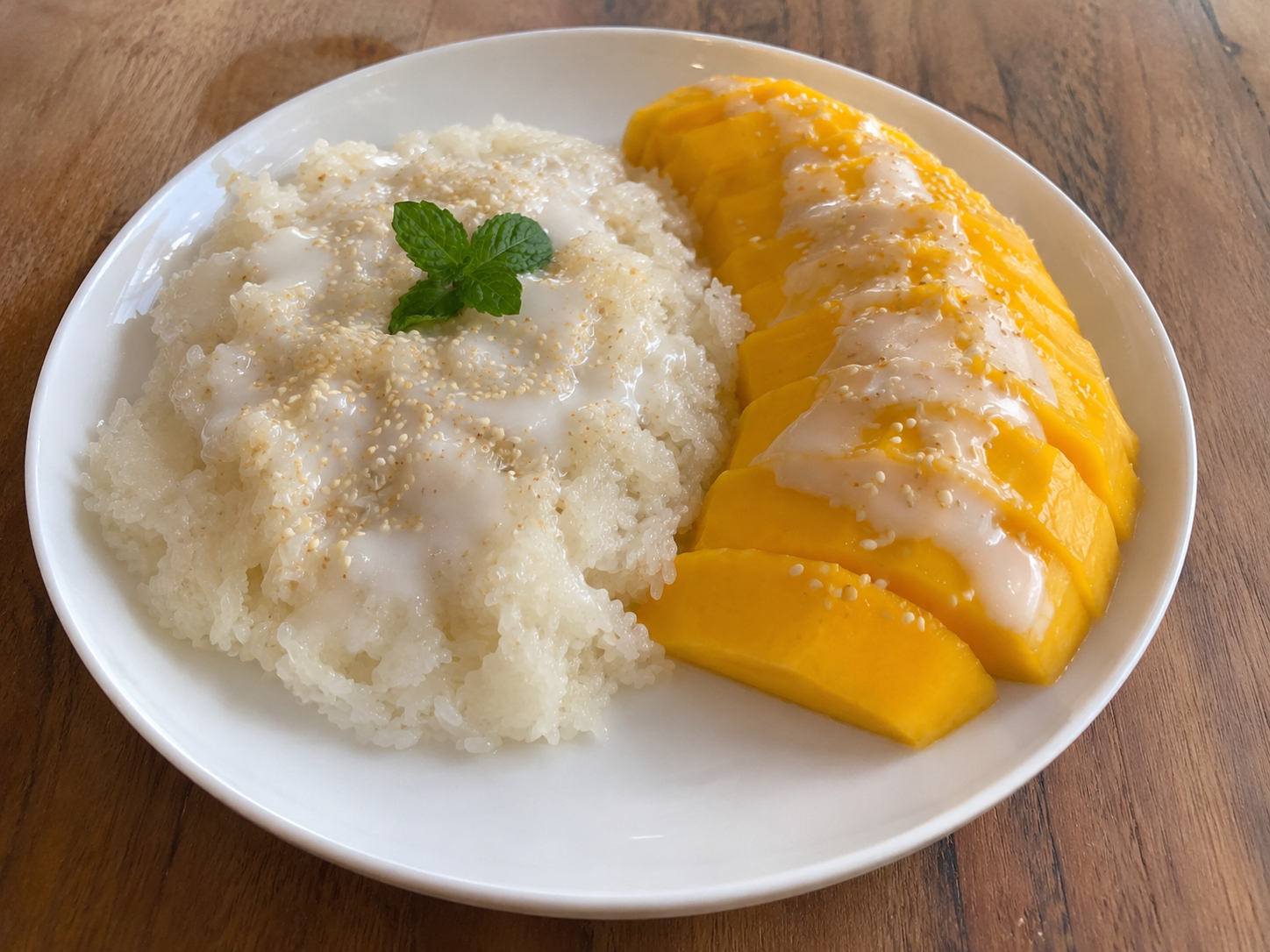Finished mango sticky rice served with ripe mango slices and coconut sauce.