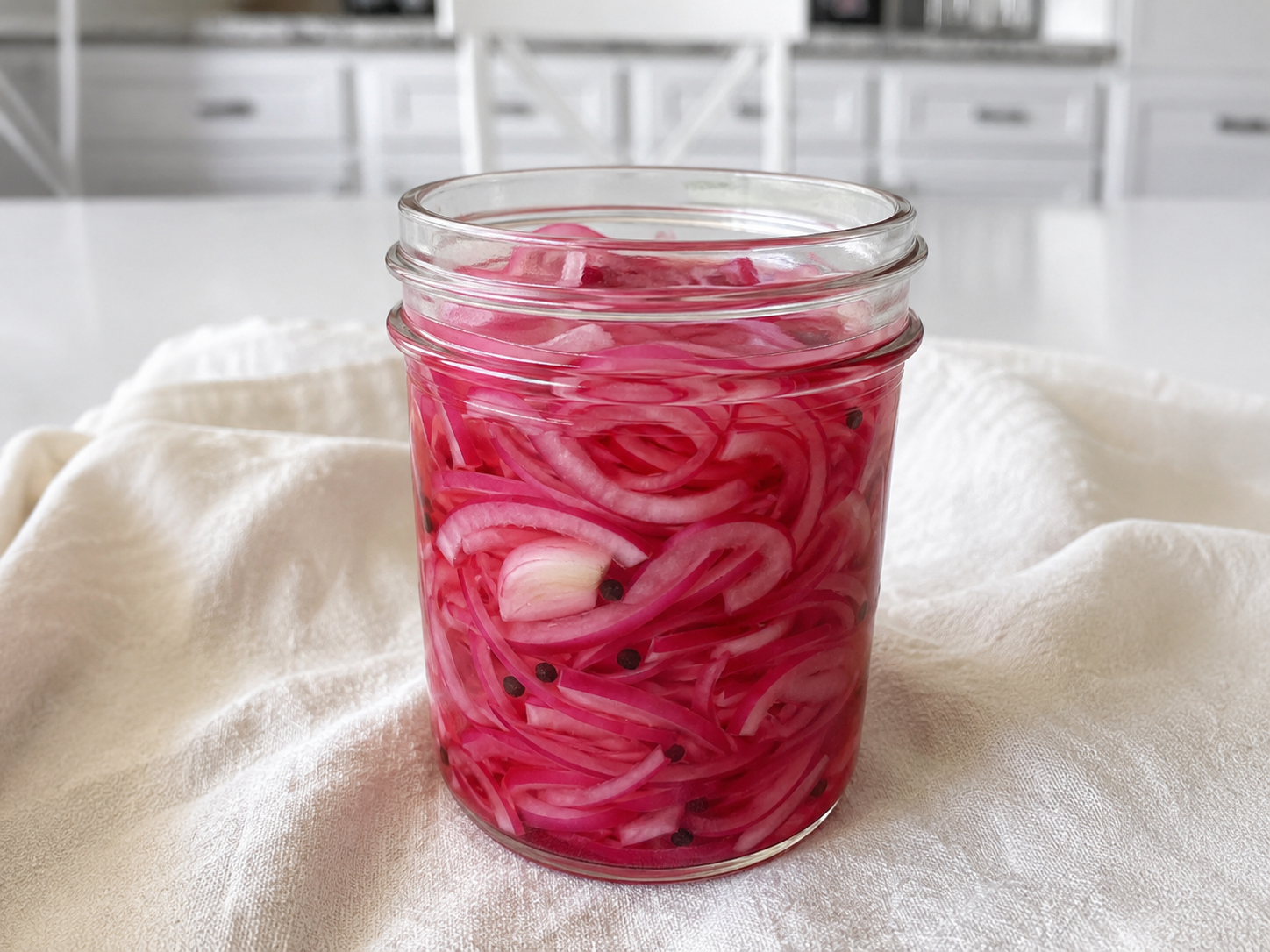 Pickled Red Onion Recipe with bright pink onion slices in a clear jar of tangy brine.