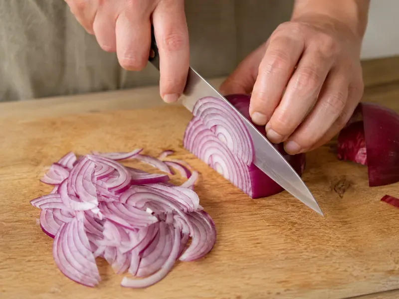 Red onion thinly sliced on a cutting board for pickling.