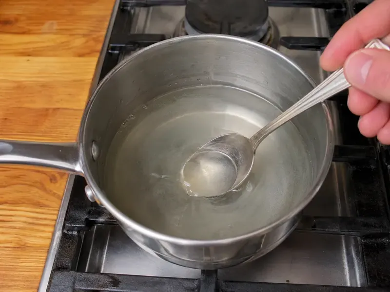 Vinegar, water, sugar, and salt warmed in a saucepan for pickling brine.