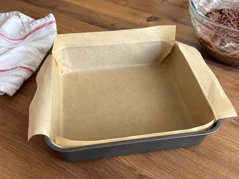 Parchment-lined baking pan prepared for raspberry crumble bars.