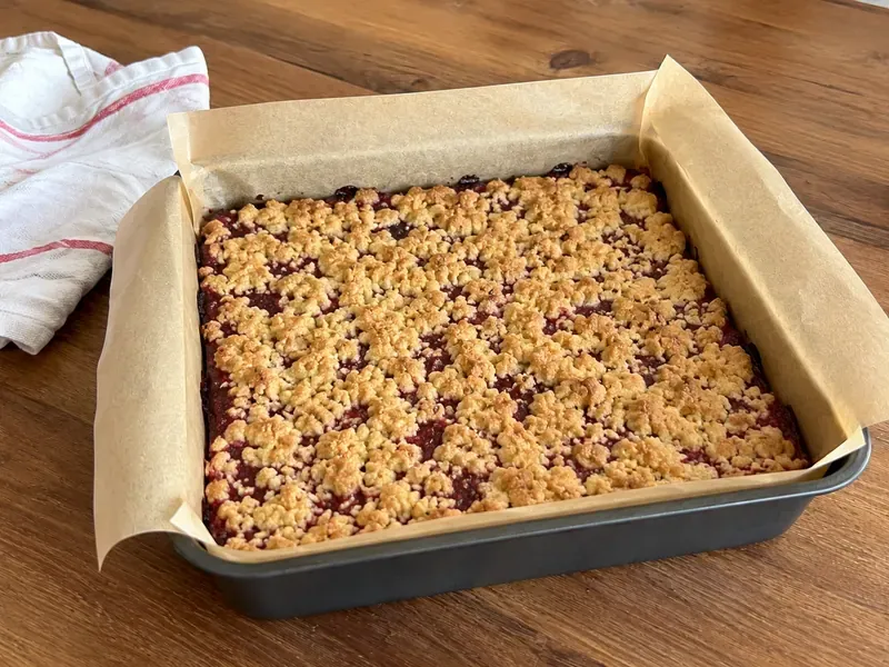 Raspberry crumble bars in the pan with a golden crumble topping before or after baking.