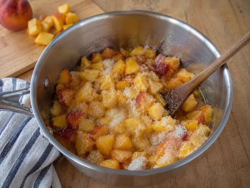 Chopped peaches mixed with sugar, lemon juice, zest, and salt in a saucepan.
