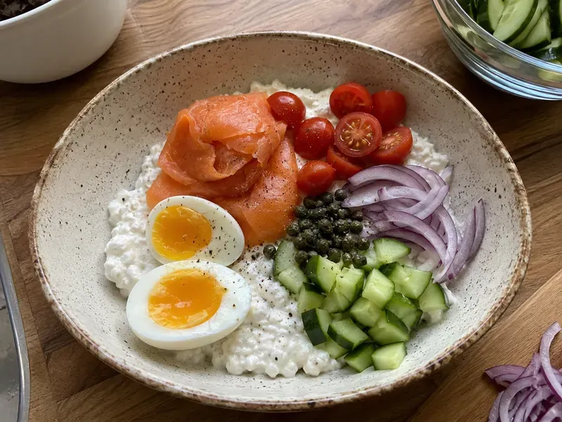 Smoked salmon cottage cheese bowl built with eggs, cucumber, tomatoes, red onion, and capers.