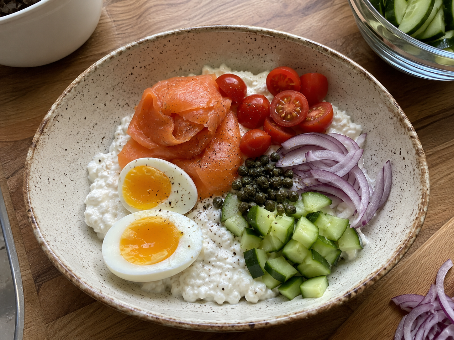 Smoked salmon cottage cheese bowl built with eggs, cucumber, tomatoes, red onion, and capers.