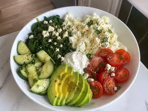 Spinach feta egg white breakfast bowl with fluffy egg whites, spinach, feta, tomatoes, cucumber, avocado, and herbs.