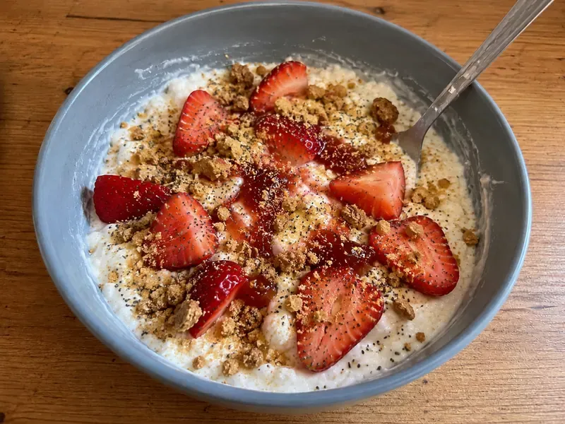 Strawberry cheesecake cottage cheese bowl topped with strawberries, graham cracker crumbs, granola, chia seeds, and strawberry jam.