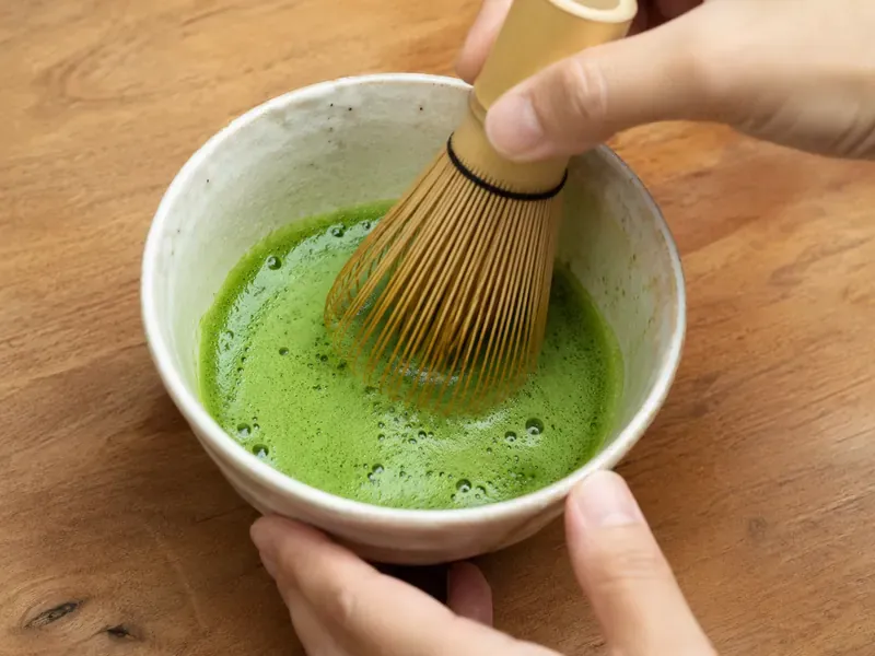 Matcha powder whisked with hot water in a small bowl.