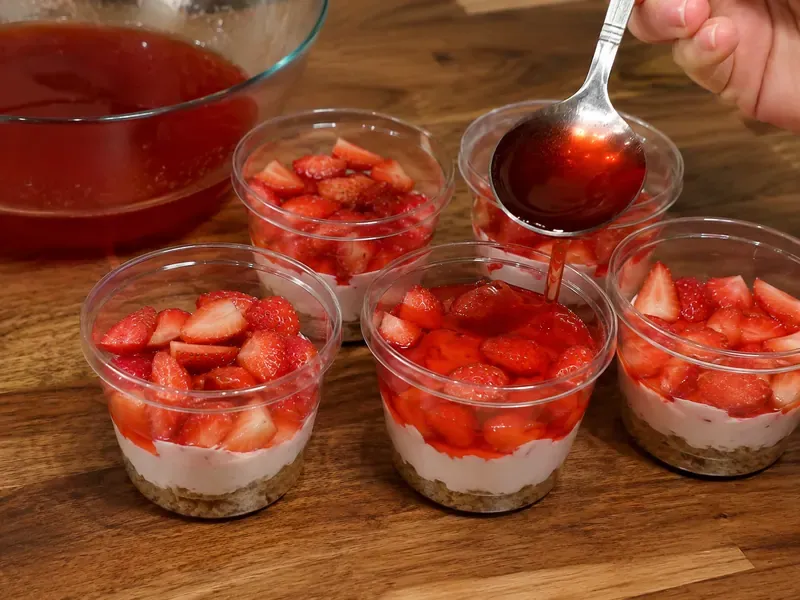 Strawberries and red gelatin added to layered dessert cups.