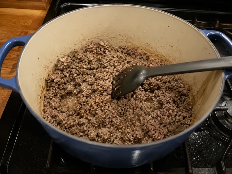 Ground beef browning in a large pot for stuffed cabbage roll soup.