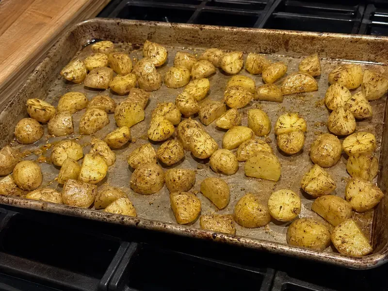 Seasoned potatoes on a sheet pan for a turkey burger protein bowl.