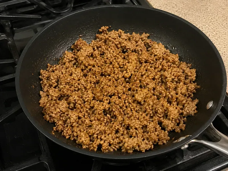 Ground turkey cooking in a skillet with burger-style seasonings.