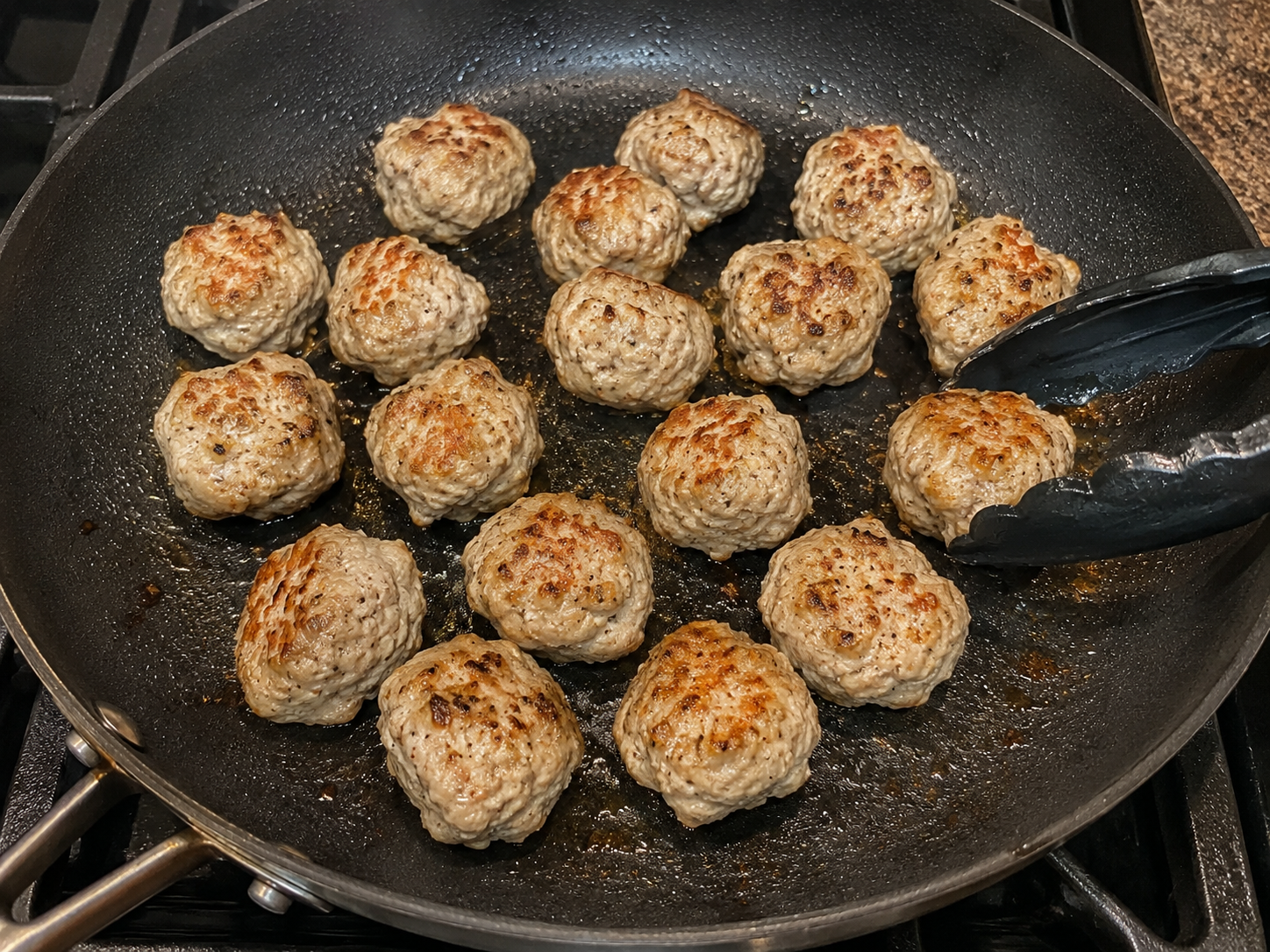 Turkey meatballs browning in a skillet with olive oil.