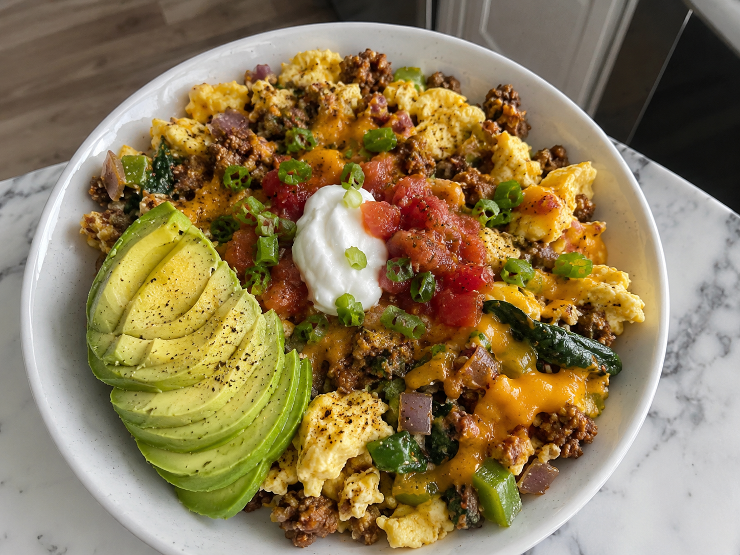 Turkey sausage egg scramble bowl with scrambled eggs, peppers, spinach, cheddar, avocado, salsa, and green onions.