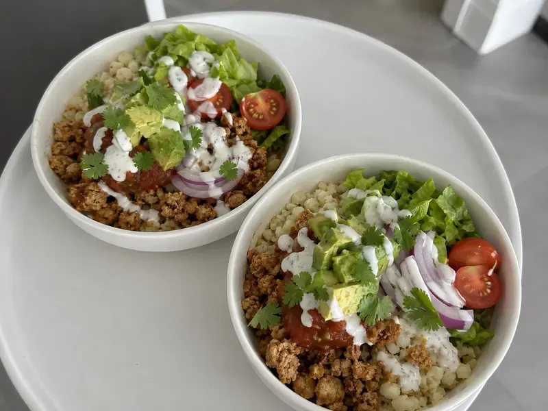 Turkey taco cauliflower rice bowl with seasoned ground turkey, cauliflower rice, lettuce, salsa, tomatoes, avocado, and lime yogurt sauce.