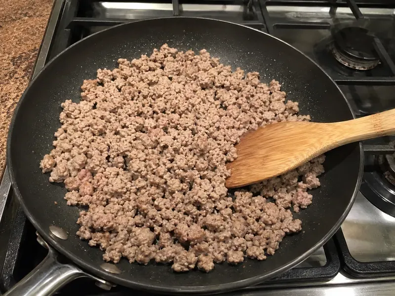 Lean ground turkey cooking in a skillet for turkey taco cauliflower rice bowls.