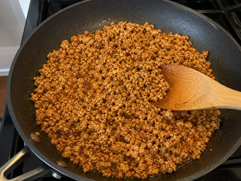 Ground turkey seasoned with taco spices in a skillet.
