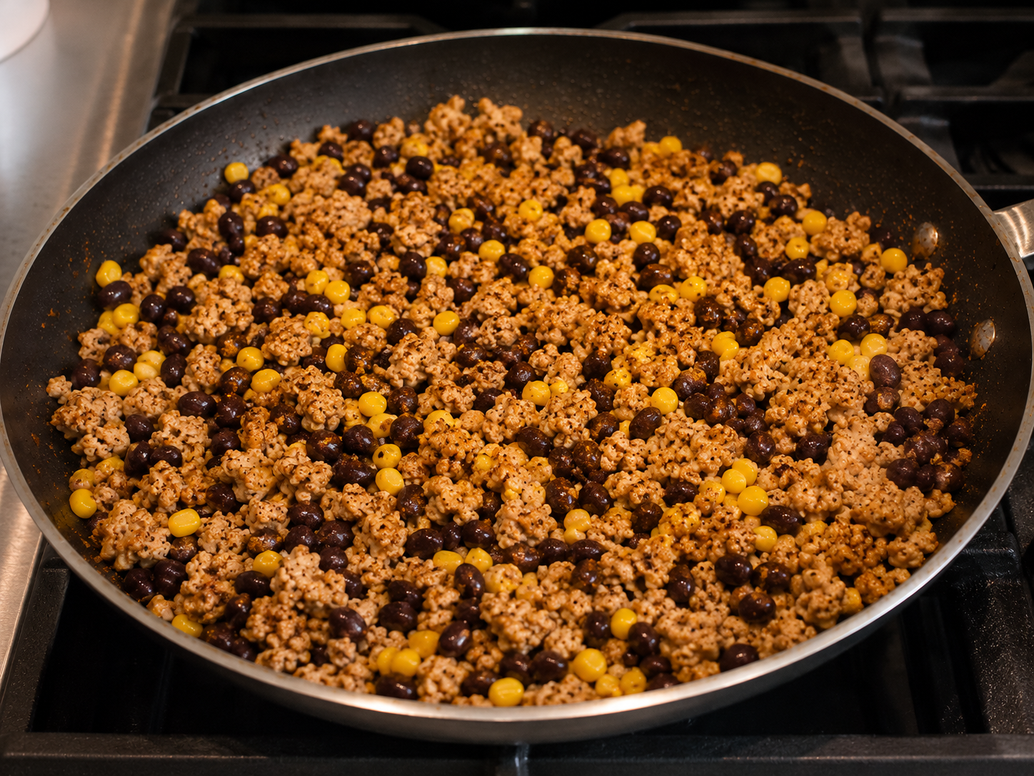Black beans and corn mixed into seasoned ground turkey in a skillet.
