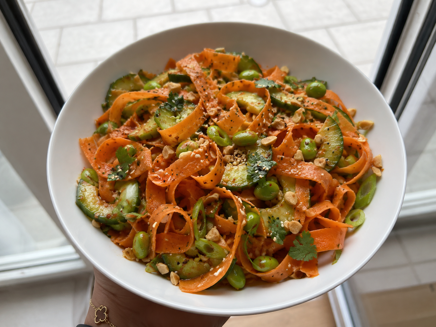Viral carrot ribbon salad with cucumber, green onions, cilantro, peanuts, sesame seeds, edamame, and soy chili sesame dressing.